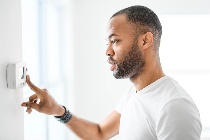 A man choosing temperature on thermostat